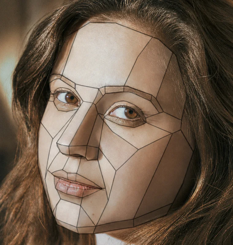 A photograph of a woman's face with a wireframe of flat planes drawn over it, breaking the forehead, temples, eye sockets, nose, cheeks, mouth and jaw into facets.